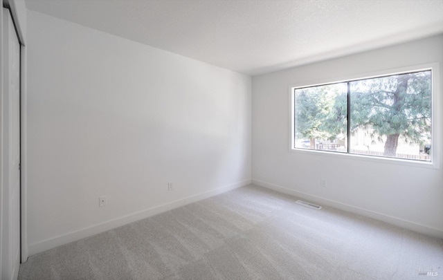 spare room with light carpet and a textured ceiling