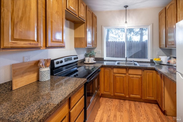 kitchen with sink, dark stone countertops, hanging light fixtures, light hardwood / wood-style floors, and electric stove