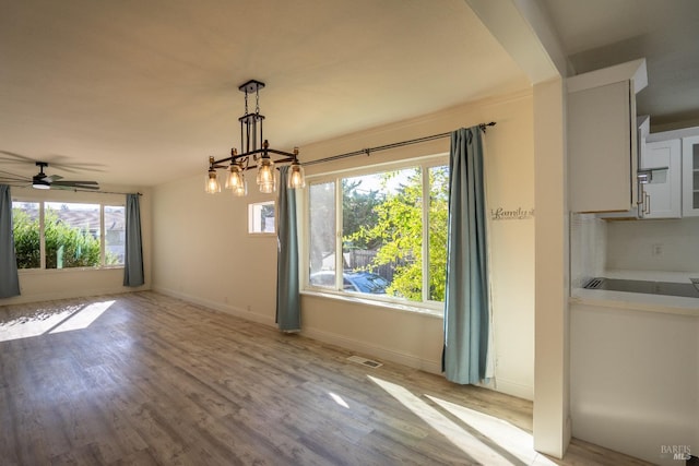 unfurnished dining area featuring ceiling fan and light wood-type flooring