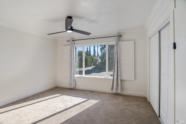 carpeted empty room featuring crown molding, ceiling fan, and a textured ceiling