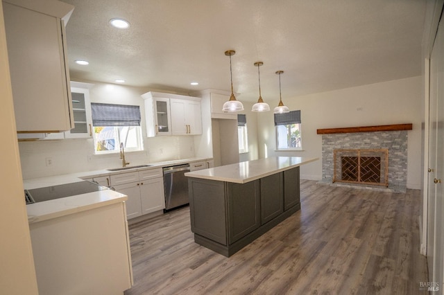 kitchen featuring a kitchen island, sink, hanging light fixtures, and white cabinets