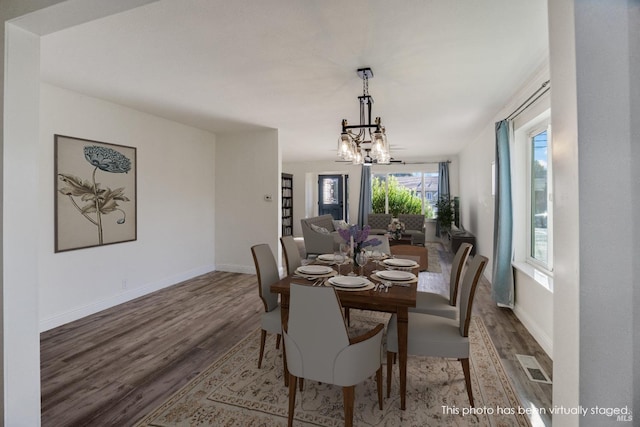 dining space with hardwood / wood-style flooring and a chandelier