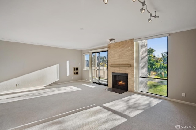 unfurnished living room with track lighting, ornamental molding, a fireplace, and light carpet