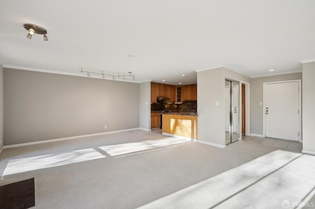 unfurnished living room with light colored carpet, ornamental molding, and rail lighting