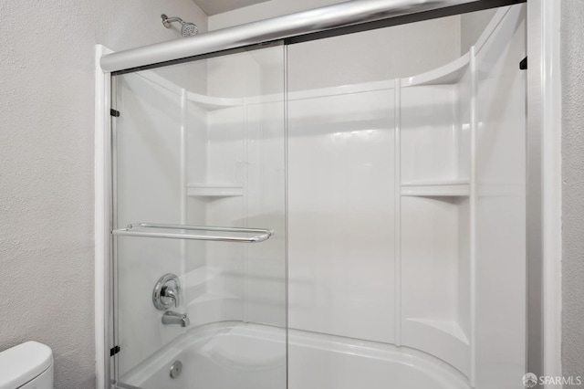 bathroom with bath / shower combo with glass door and toilet