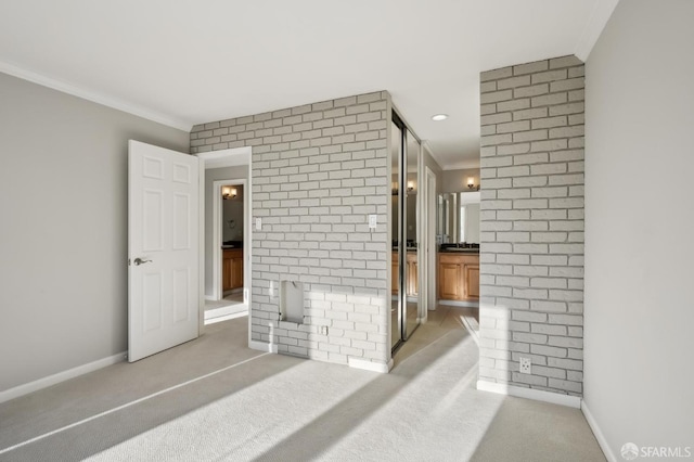 interior space featuring light colored carpet, ornamental molding, and brick wall