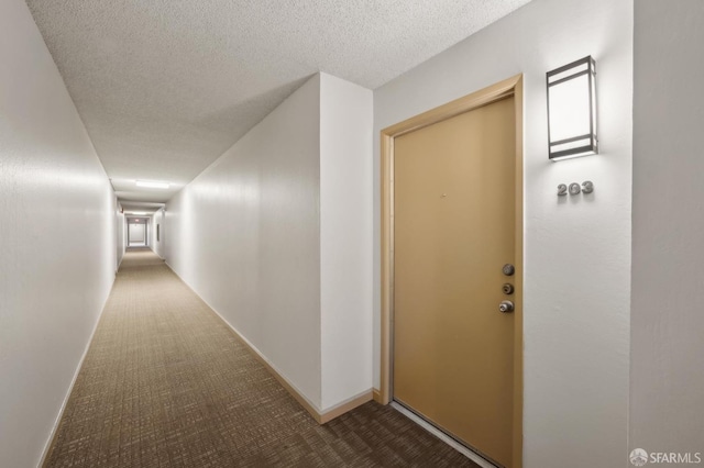 corridor featuring a textured ceiling and carpet flooring