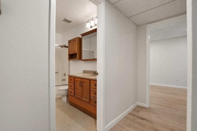 bathroom featuring vanity, baseboards,  shower combination, toilet, and visible vents