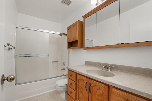 bathroom featuring combined bath / shower with glass door, vanity, tile patterned flooring, toilet, and visible vents