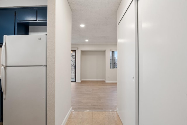 hall featuring a textured ceiling, light tile patterned floors, baseboards, and recessed lighting