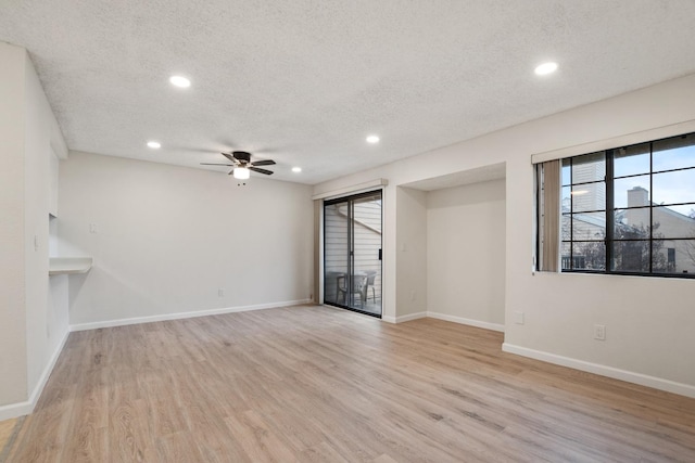 interior space with light wood-style flooring, ceiling fan, baseboards, and a textured ceiling