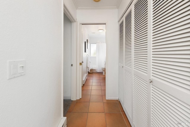 corridor featuring ornamental molding and light tile patterned flooring