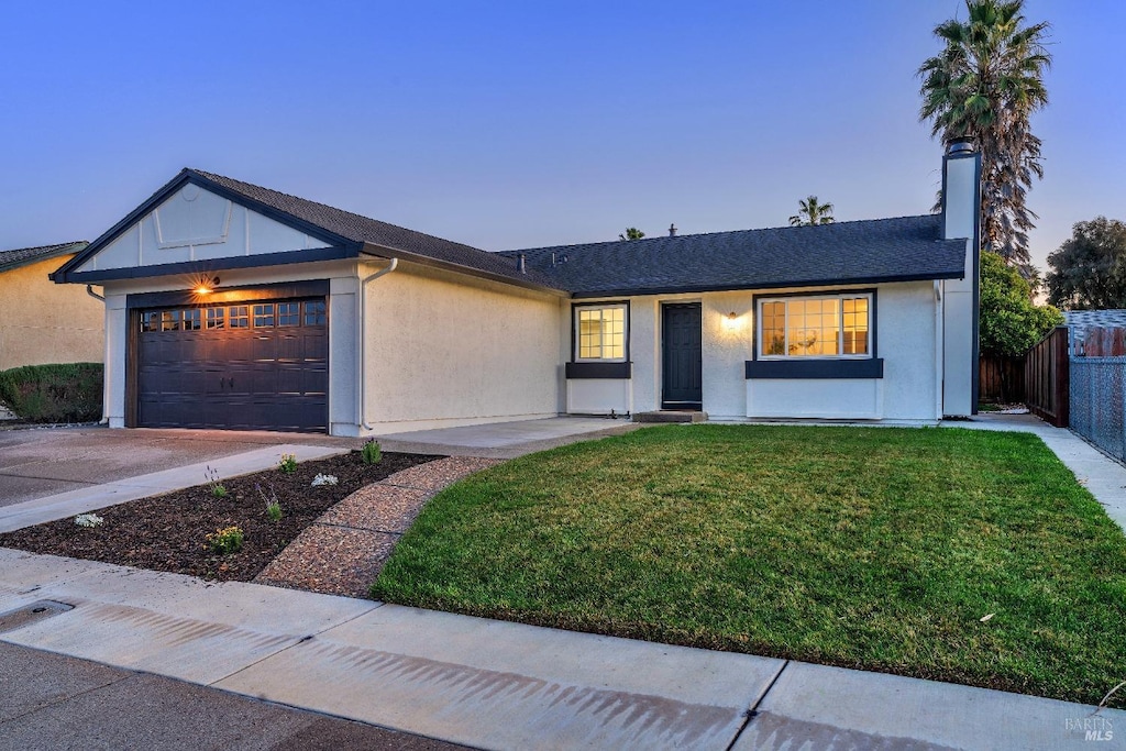 ranch-style house featuring a garage and a lawn