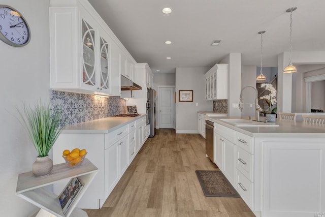 kitchen featuring decorative light fixtures, sink, white cabinets, stainless steel appliances, and light wood-type flooring