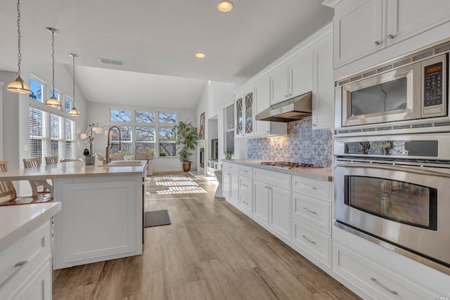 kitchen featuring sink, vaulted ceiling, hanging light fixtures, appliances with stainless steel finishes, and white cabinets