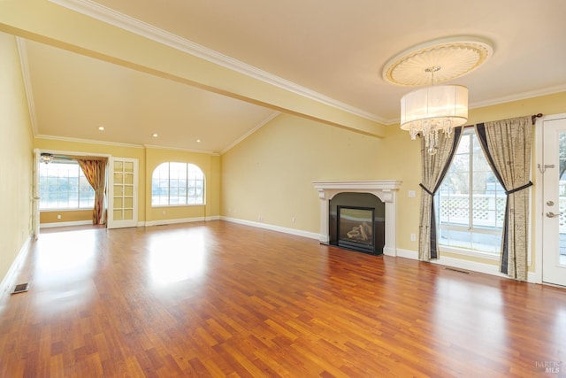 unfurnished living room featuring an inviting chandelier, hardwood / wood-style floors, and crown molding