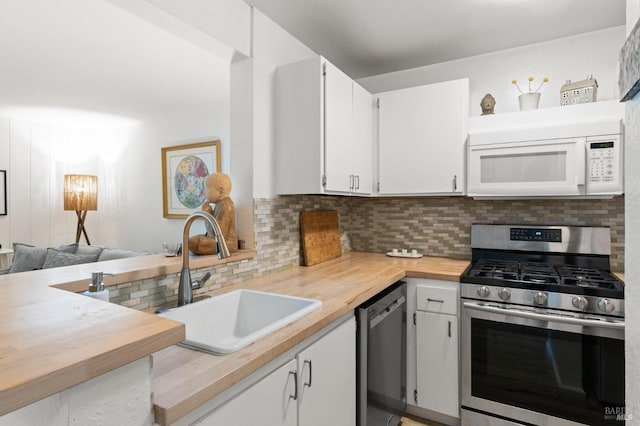 kitchen featuring dishwashing machine, sink, stainless steel gas range, white cabinets, and decorative backsplash