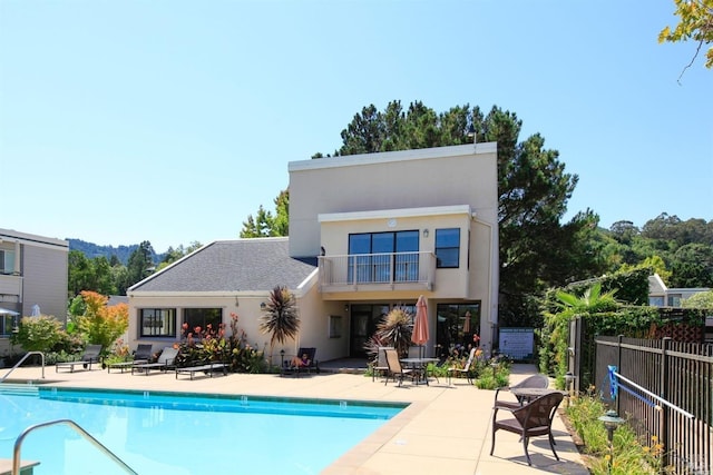 back of property featuring a community pool, a patio area, and a balcony