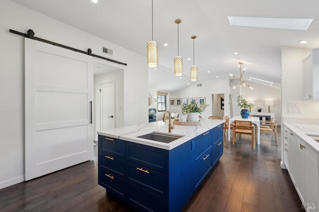 kitchen featuring blue cabinets, sink, white cabinets, a kitchen island with sink, and a barn door