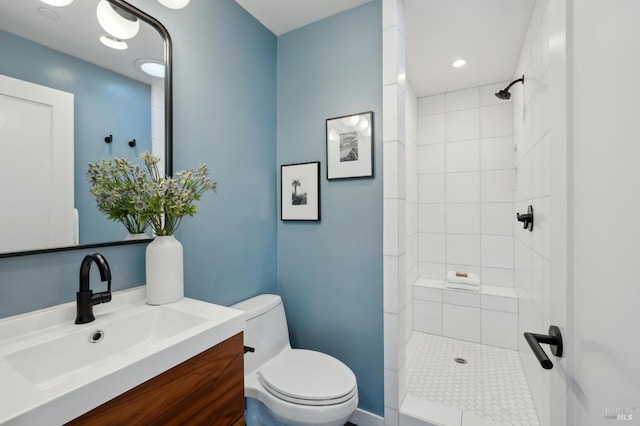 bathroom featuring tiled shower, vanity, and toilet