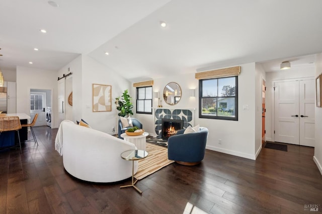 living room with lofted ceiling, a barn door, dark hardwood / wood-style flooring, and washer / clothes dryer