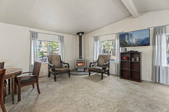 sitting room featuring plenty of natural light, vaulted ceiling with beams, a wood stove, and carpet