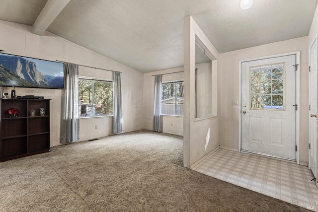 entryway with tile patterned floors, a textured ceiling, vaulted ceiling with beams, and carpet