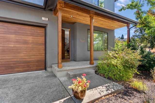 view of exterior entry featuring covered porch and a garage