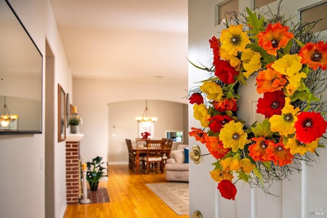 hall featuring arched walkways, a notable chandelier, and wood finished floors