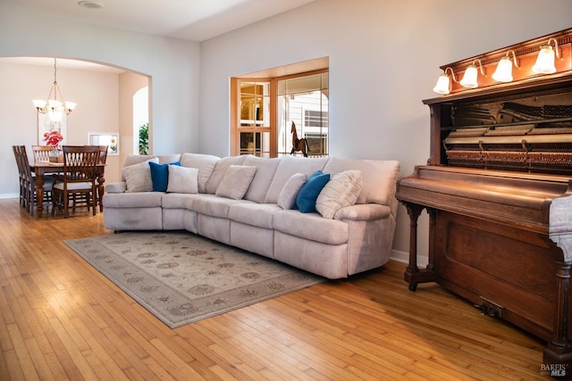 living room featuring hardwood / wood-style floors, an inviting chandelier, baseboards, and arched walkways