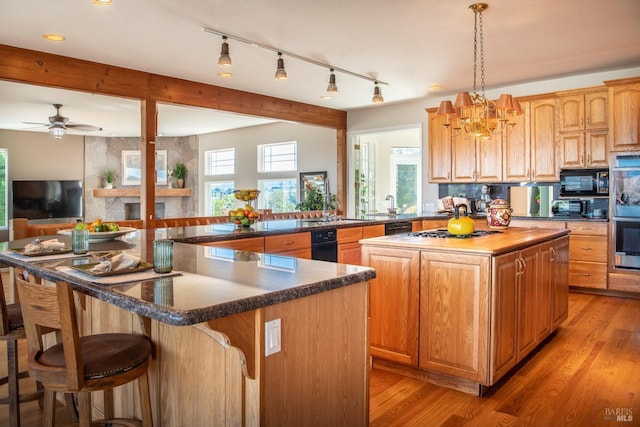 kitchen featuring light wood-style floors, a kitchen island, black appliances, and beamed ceiling