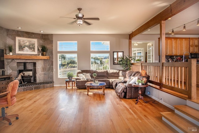 living room with track lighting, baseboards, ceiling fan, beam ceiling, and light wood-style flooring