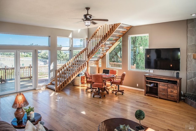 living room featuring baseboards, a ceiling fan, wood finished floors, and stairs