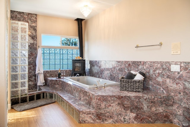 bathroom featuring a wood stove, a garden tub, and wood finished floors