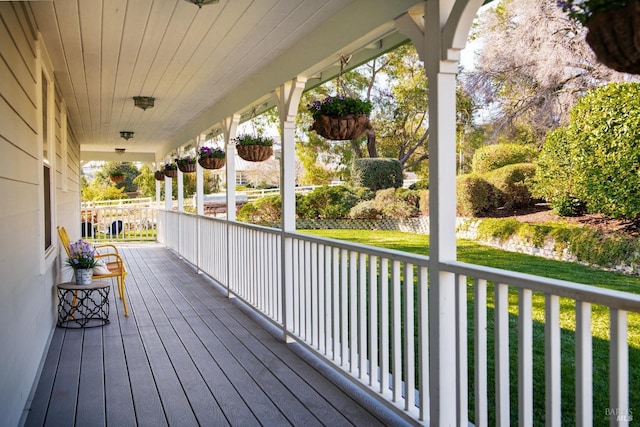 wooden deck featuring covered porch and a yard