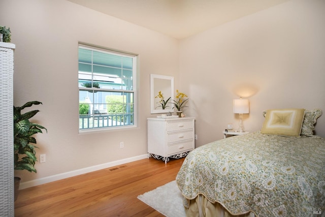 bedroom featuring visible vents, baseboards, and wood finished floors