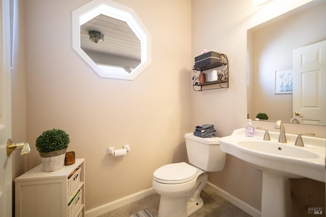 bathroom featuring toilet, baseboards, and a sink