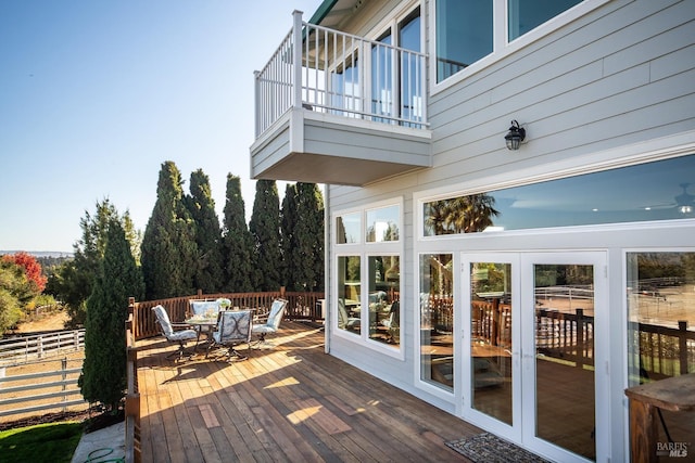 wooden deck featuring french doors, outdoor dining space, and fence