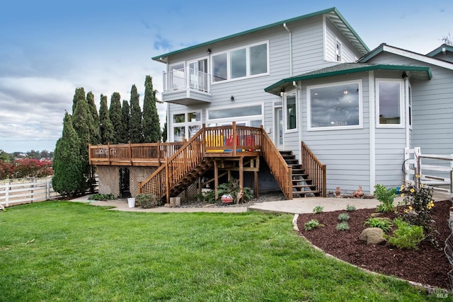 back of property with a balcony, stairway, fence, and a lawn