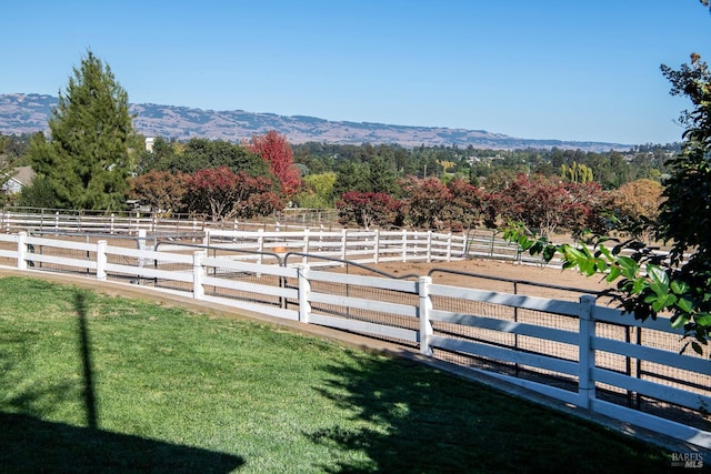 view of yard featuring a rural view, fence, and a mountain view