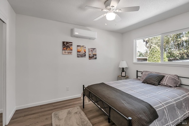 bedroom featuring ceiling fan, dark wood-type flooring, a textured ceiling, and a wall unit AC