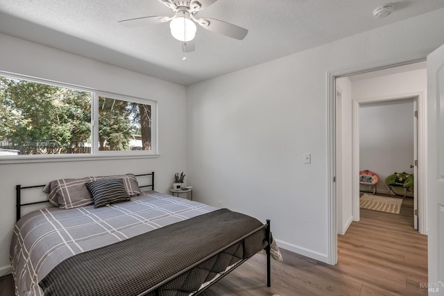 bedroom with hardwood / wood-style flooring, ceiling fan, and a textured ceiling