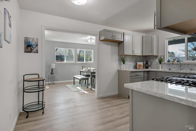 kitchen with gray cabinets, light stone countertops, sink, and decorative backsplash