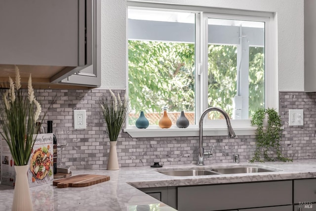 kitchen featuring light stone counters, sink, a wealth of natural light, and gray cabinets