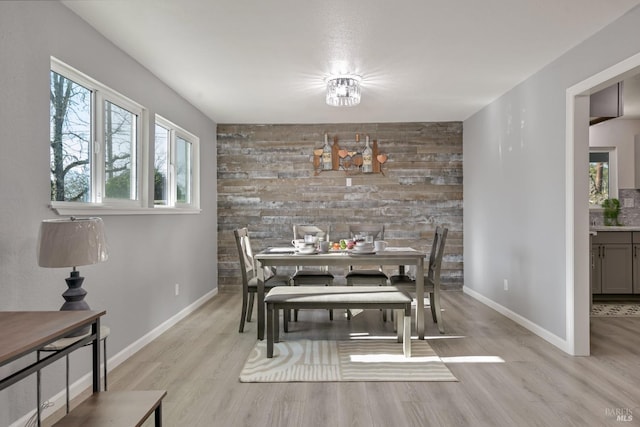 dining space with light hardwood / wood-style flooring and wood walls