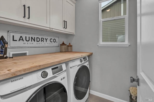 clothes washing area featuring cabinets and washer and dryer