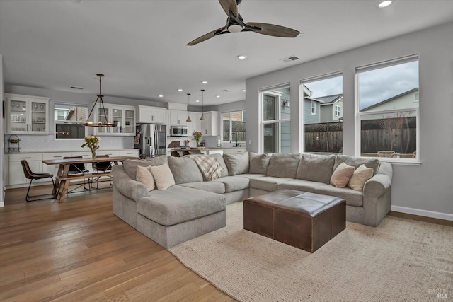 living room with sink, light hardwood / wood-style floors, and ceiling fan