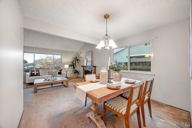 carpeted dining room featuring vaulted ceiling, a brick fireplace, a textured ceiling, and a chandelier