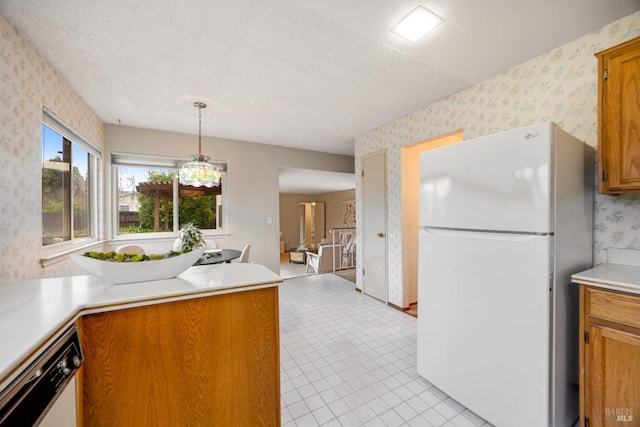 kitchen featuring hanging light fixtures, white appliances, and a textured ceiling