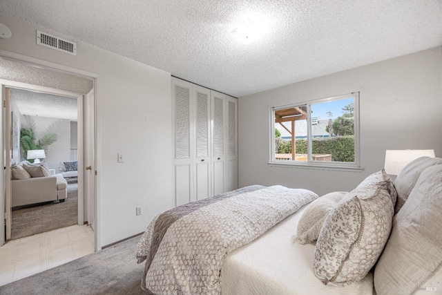 bedroom featuring light colored carpet, a textured ceiling, and a closet